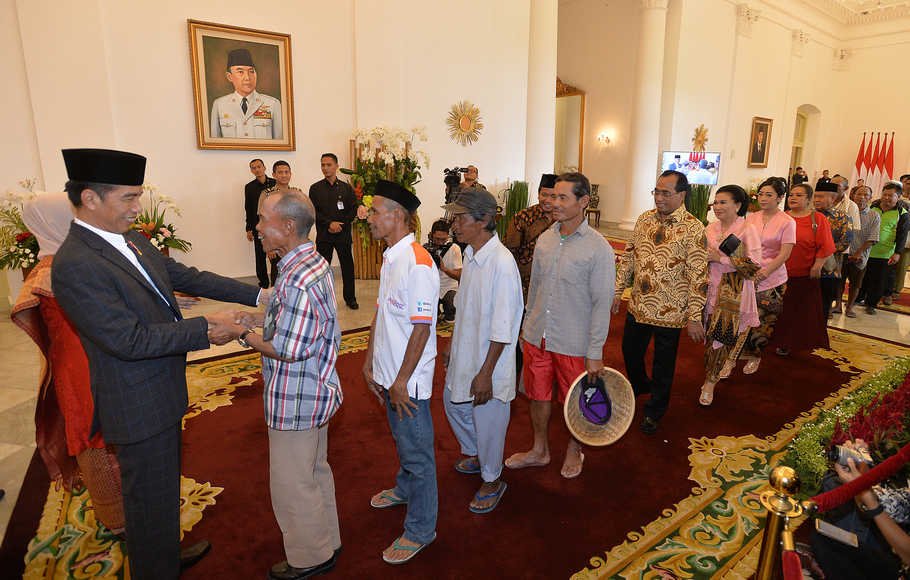 Presiden Joko Widodo (kiri) berjabat tangan dengan warga di acara Silahturahmi Idul Fitri 1 Syawal 1439 H di Istana Kepresidenan Bogor, Jawa Barat, Jumat (15/6).